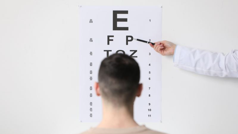 Optometrista evaluando agudeza visual con tabla optométrica en consultorio laboral