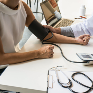 Médico especialista en Medicina Laboral revisando signos vitales y tomando notas en tablet a un trabajador durante un examen periódico de salud ocupacional. Ambiente de consultorio moderno y profesional.